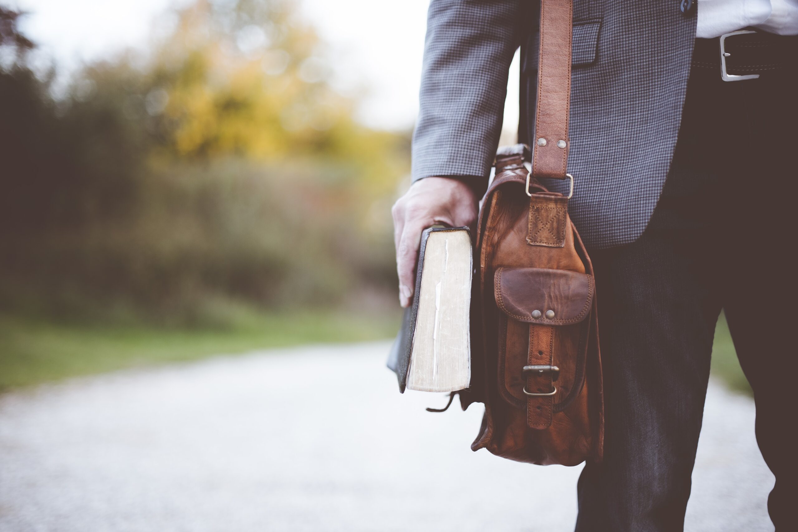 A closeup shot of a male wearing a bag and hilding the bible with a blurred background